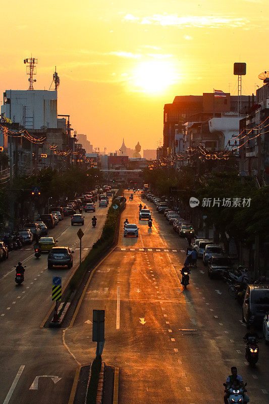 橙色的夕阳天空在佛祖Dhammakaya Thep Mongkol(青铜雕像)和Wat Paknam Bhasicharoen(皇家寺庙)之上，从立交桥上看高速公路上的交通堵塞，摩托车，汽车，空气污染，烟雾，汽车烟雾，重点在前景